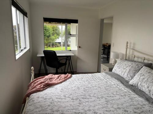 a bedroom with a bed and a desk and a window at Coastal Guest Suite near Fishermans Cove in Whangaparaoa