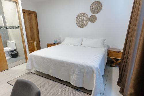 a bedroom with a white bed and a chair at Hotel Punto Oriente Tonala in Tonalá