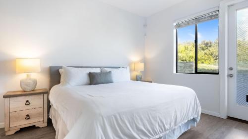 a white bedroom with a bed and a window at Strand Way B by AvantStay in Oceano