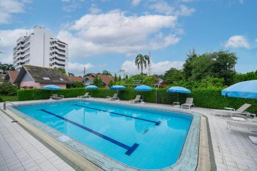 a large swimming pool with chairs and umbrellas at Bangkok Rama Hotel in Bangkok