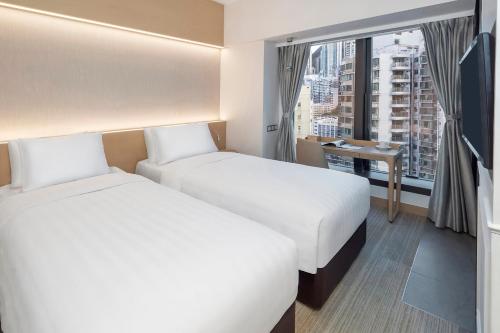 two beds in a hotel room with a window at Y Hotel Hong Kong in Hong Kong