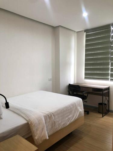 a bedroom with a bed and a desk and a window at GQ Apartment in Aklan
