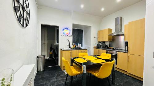 a kitchen with a dining table and yellow chairs at Spacious 3 Bedroom Entire Apartment Self Check in & Free Parking in Cowdenbeath