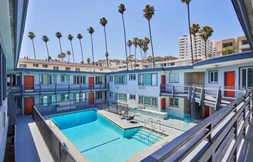 a building with a swimming pool and palm trees at Hollywood Blvd Prime Location Walk to Attractions with Pool and Free Parking in Los Angeles