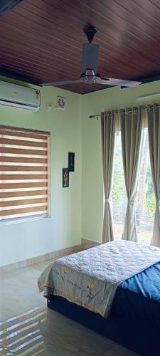 a bedroom with a bed and two windows at Riverfolk Stays in Thodupuzha