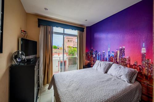 a bedroom with a purple wall with a bed and a window at Luxury Penthouse in Tuxpan