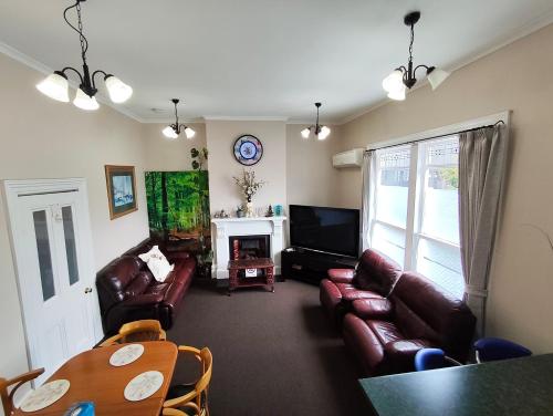 a living room with leather couches and a television at 5 Large Bedroom Villas Suitable for 10People (CBD) in Christchurch