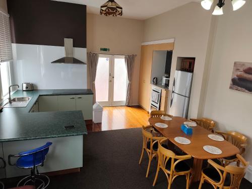 a kitchen and a dining room with a wooden table at 5 Large Bedroom Villas Suitable for 10People (CBD) in Christchurch