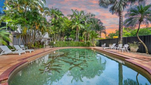 a swimming pool with chairs and palm trees at The Condo at Northshore Tower in Cairns North
