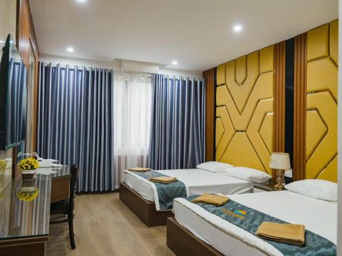 a hotel room with two beds and a desk at Ruby 25 Hotel in Hà Ðông