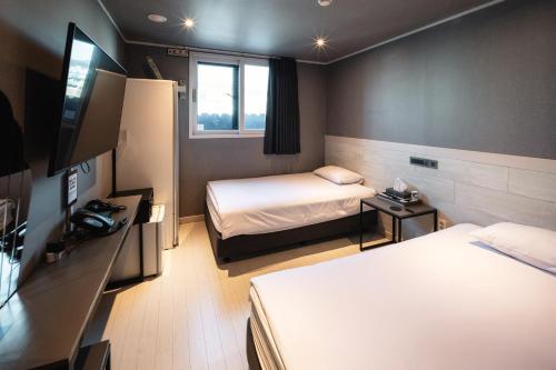 una camera d'albergo con due letti e una TV a schermo piatto di Hotel Iam a Suncheon