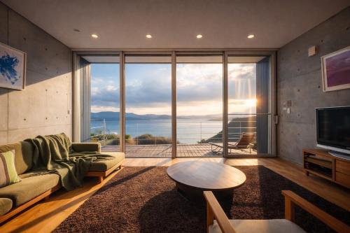 a living room with a couch and a table and a large window at #24 -牛窓villa-ペット同伴 BBQも楽しめる贅沢Villa in Kashino