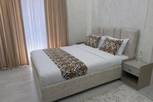 a bedroom with a bed and a nightstand with a bed sidx sidx at Mumtoz Hotel in Samarkand