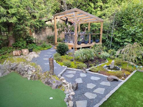 a garden with a wooden gazebo in the middle at Modern Coastal 2BR Retreat with Private Hot Tub in Vancouver BC in West Vancouver