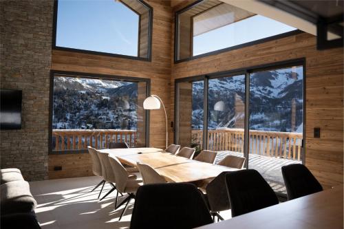 a dining room with a table and chairs and windows at Chalet 1480 in Allos