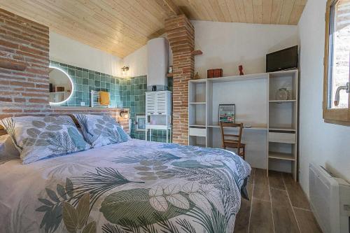 a bedroom with a bed and a brick wall at Le cabanon in Mauressac