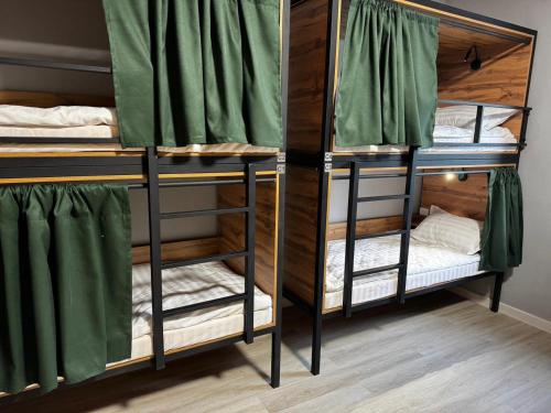 two bunk beds in a room with green curtains at HOSTEL Q7 Almaty in Almaty