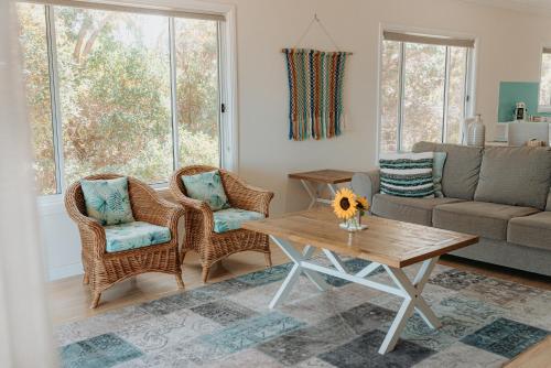 a living room with a couch and chairs and a table at Aldinga Bay Bungalow Ocean View Retreat in Sellicks Beach