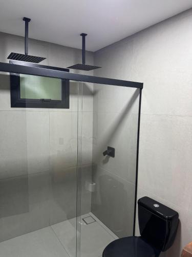 a bathroom with a glass shower with a toilet at Refúgio do Morro - Cabana 1 in Torres