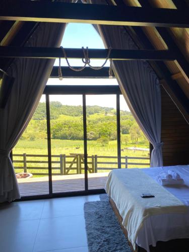 a bedroom with a bed and a large window at Refúgio do Morro - Cabana 1 in Torres