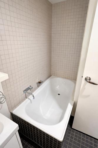 a bath tub in a bathroom with white tiles at Mega Style Apartments Tribeca in Melbourne