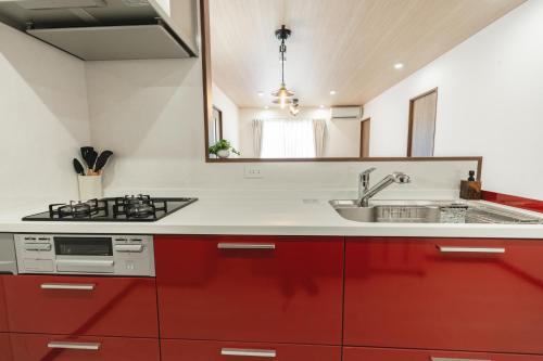 a kitchen with red cabinets and a sink at Value Residence Hotel 久貝 in Miyako-jima