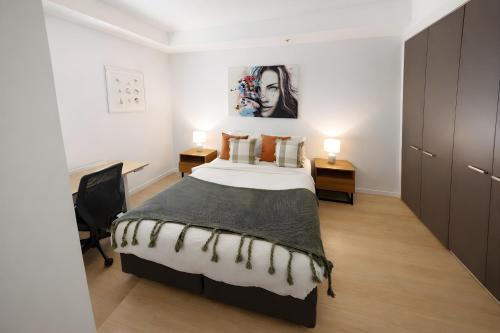 a bedroom with a bed and a desk and two lamps at Mega Style Apartments Tribeca in Melbourne