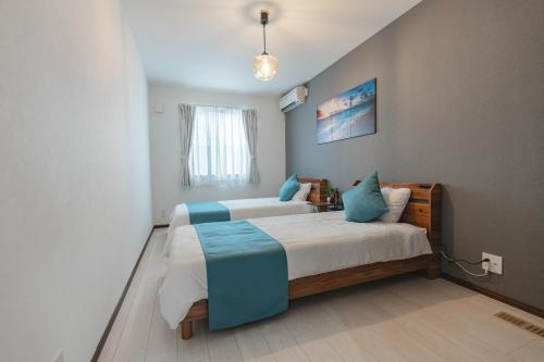 a bedroom with two beds with blue pillows at Value Residence Hotel 久貝 in Miyako-jima