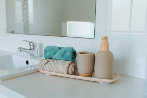 a tray with towels and a bottle on a bathroom counter at Aldinga Bay Bungalow Ocean View Retreat in Sellicks Beach