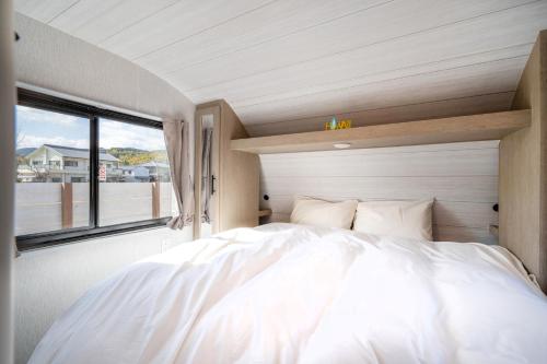 a large white bed in a room with a window at Glamping Trailer Lanikai in Awaji