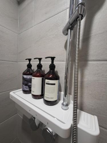 a shelf in a bathroom with three bottles of soap at Ocean View Hotel near Incheon Airport in Chagyak-to