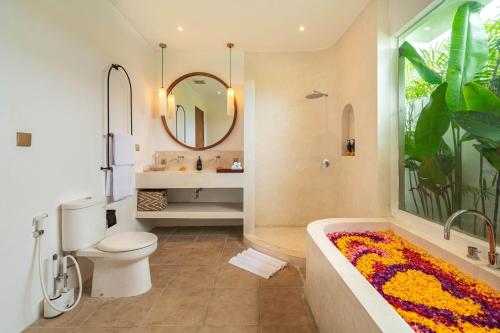 a bathroom with a tub and a toilet and a mirror at Villa Arlo Canggu in Canggu