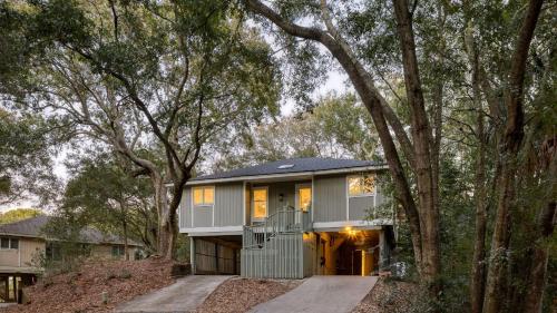 a house in the woods with a garage at Conch Cottage by AvantStay Walk to Beach Deck Fireplace Outdoor Dining in Isle of Palms