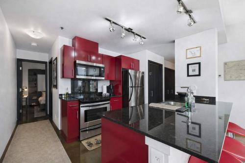 a kitchen with red cabinets and a black counter top at Modern Beltline Escape Sky-High Views DT Views in Calgary