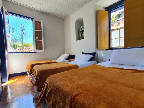 a room with three beds and two windows at Pouso History in Ouro Preto