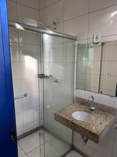 a bathroom with a sink and a glass shower at Pouso History in Ouro Preto