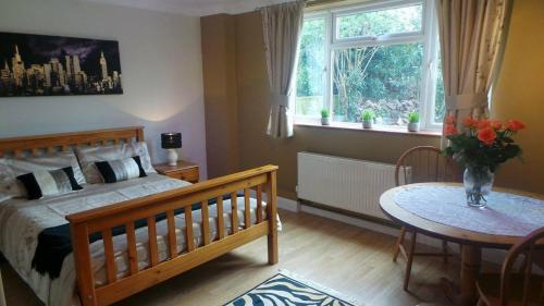 a bedroom with a bed and a table and a window at Chimneys B&B in Ipswich