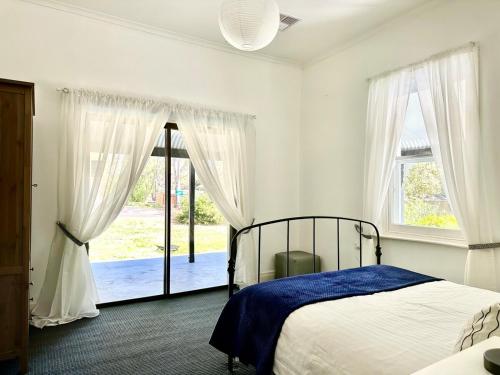a bedroom with a bed and a large window at Clare Cottage on Wendouree in Clare