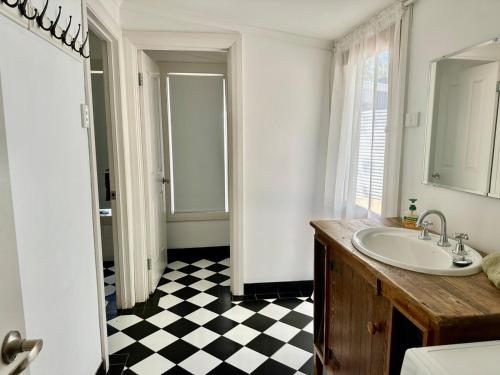 a bathroom with a sink and a black and white checkered floor at Clare Cottage on Wendouree in Clare