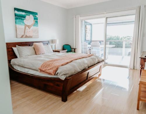 a bedroom with a large bed and a balcony at Aldinga Bay Bungalow Ocean View Retreat in Sellicks Beach