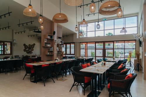 a dining room with tables and chairs and windows at Rawayana West Villas & Kids Park in Rawai Beach