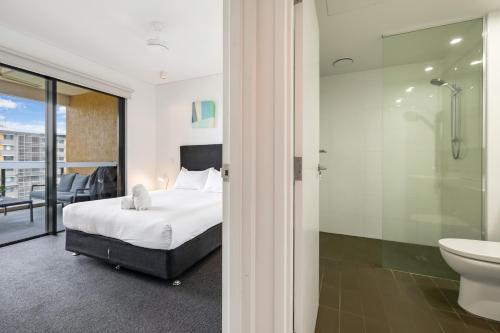 a bedroom with a bed and a bathroom with a shower at Darwin Waterfront Short Stay Apartments in Darwin