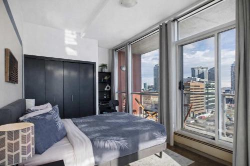 a bedroom with a bed and a large window at Modern Beltline Escape Sky-High Views DT Views in Calgary