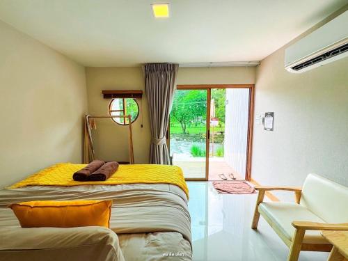 a bedroom with a bed and a chair and a window at ชิลล์ แคมป์ ชะอม in Ban Bung Mai