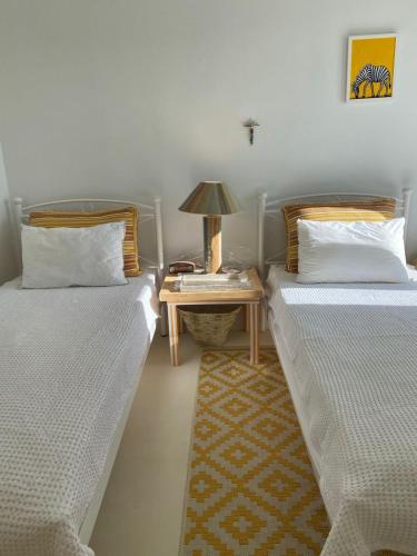 two beds in a room with a side table at Lobster House Antiparos in Antiparos