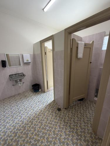 a bathroom with a toilet and a sink and a door at Coffs Harbour Hotel in Coffs Harbour