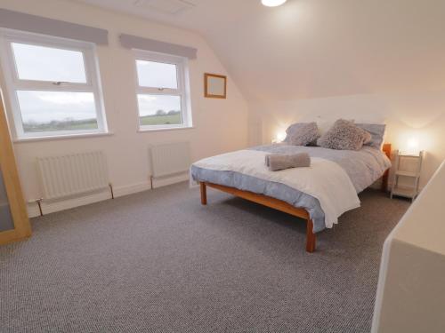 a bedroom with a bed and two windows at The Loft - 96B in Articlave