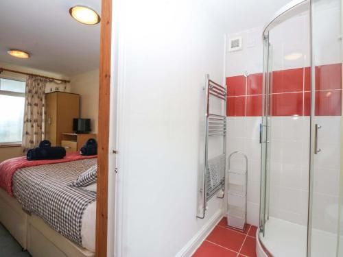 a bedroom with a bed and a glass shower at Min Y Traeth in Amlwch