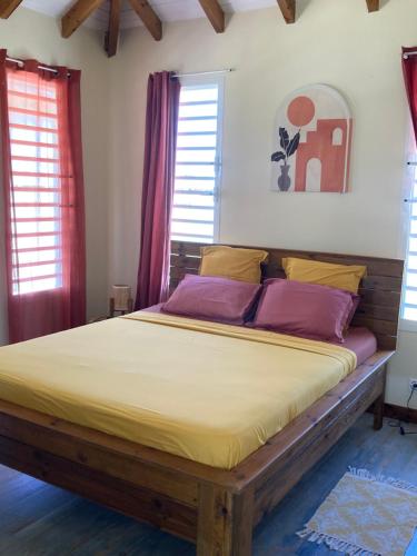 a bedroom with a large bed with yellow and purple pillows at La villa Surette in Capesterre
