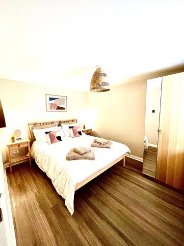 a bedroom with a large white bed with wooden floors at Harbour Hideaway, Porthleven in Porthleven